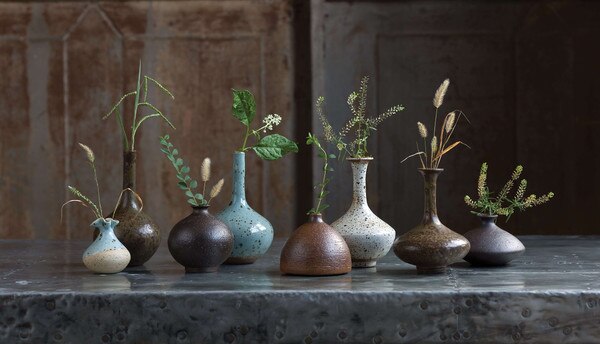 eight earth colored porcelain bud vases on a metal floor